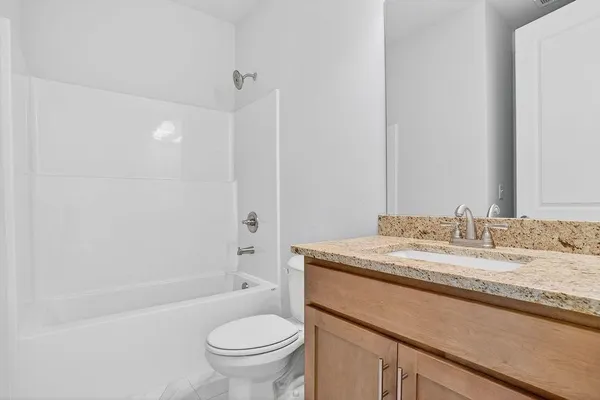 a bathroom with a granite countertop sink toilet mirror vanity and bathtub
