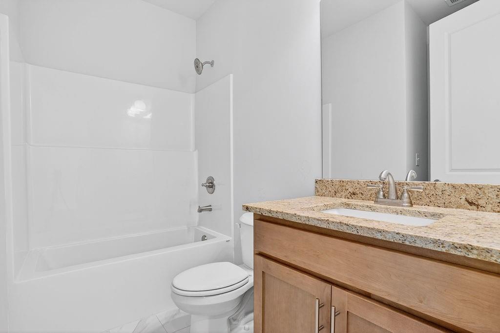 152 Classic Overlook Homer, GA 30547 - Photo 4 of 36 a bathroom with a granite countertop sink toilet mirror vanity and bathtub