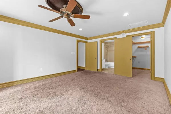 an empty room with closet and a ceiling fan
