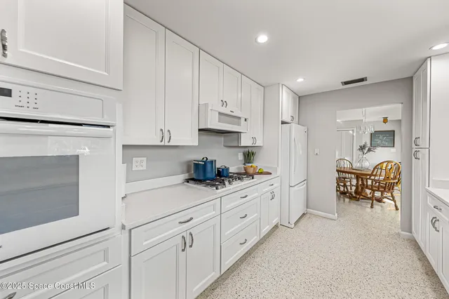 a kitchen with white cabinets and sink
