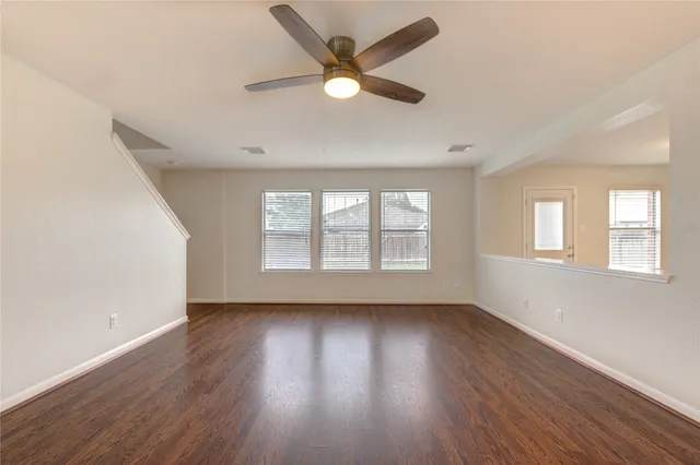 an empty room with wooden floor and windows