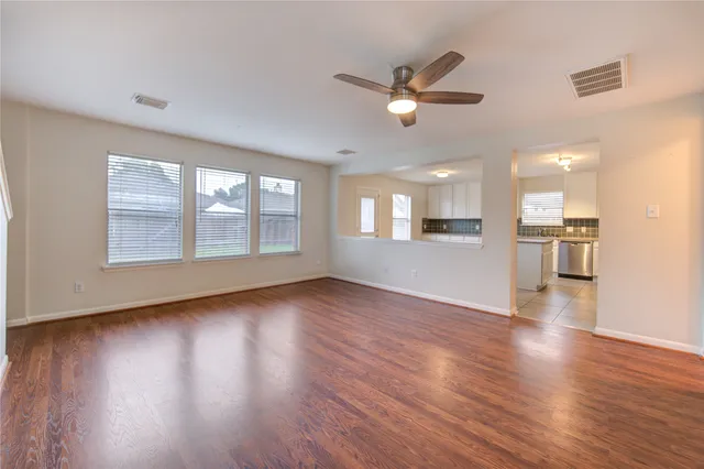 a view of an empty room with wooden floor and a window