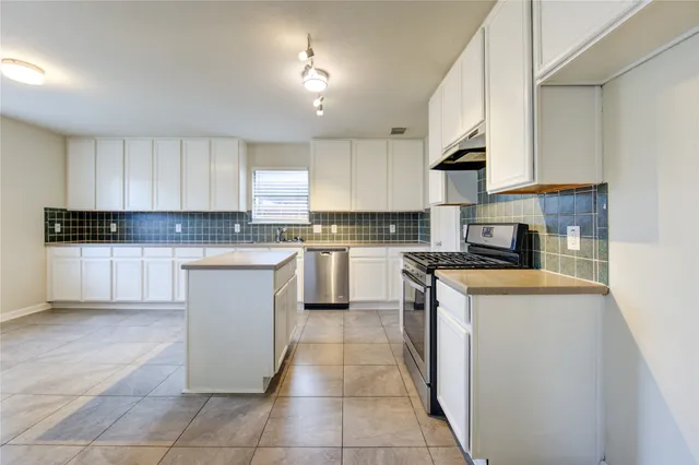 a kitchen with a stove sink and cabinets