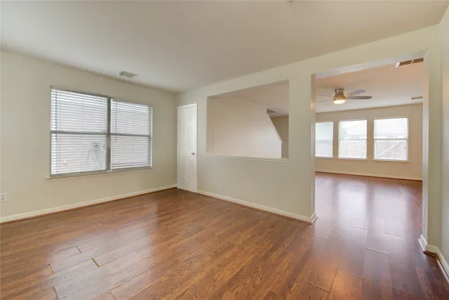 an empty room with wooden floor and windows