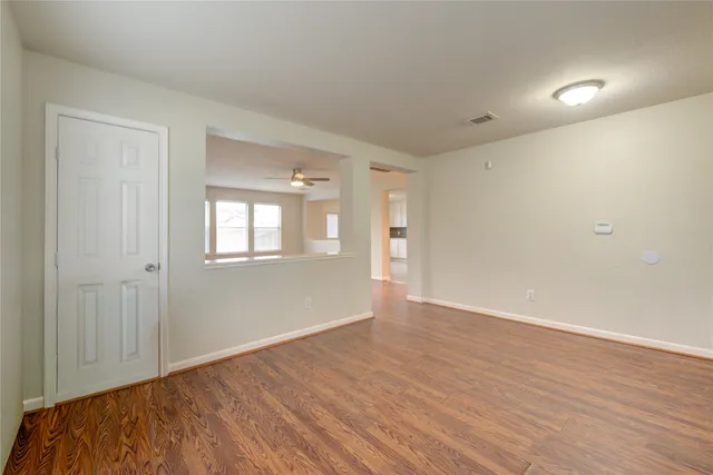 a view of an empty room with wooden floor and a window