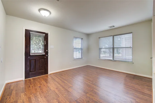 a view of an empty room with window and wooden floor
