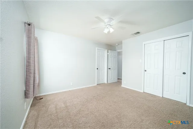 an empty room with window and ceiling fan