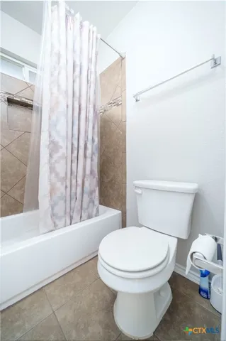 a white toilet sitting next to a bath tub and a shower