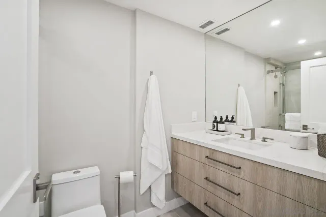 a bathroom with a double vanity sink toilet and a mirror