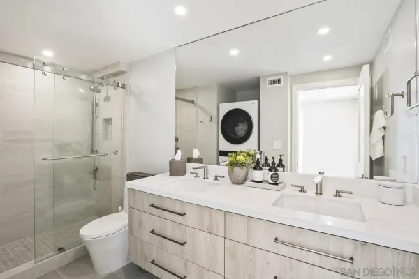 a bathroom with a double vanity sink toilet mirror and shower