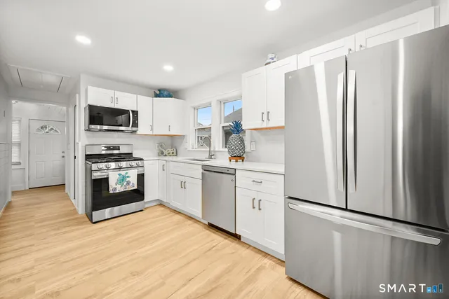 a kitchen with white cabinets and stainless steel appliances
