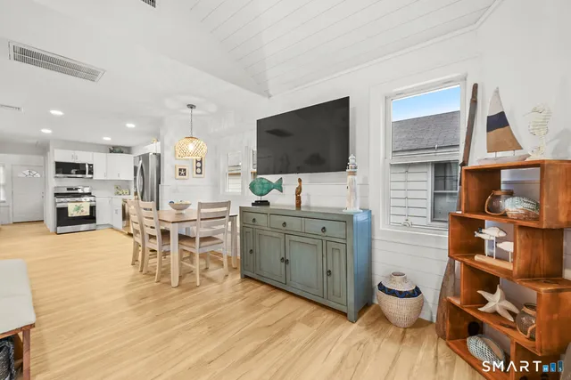 a room with furniture a flat screen tv and kitchen view