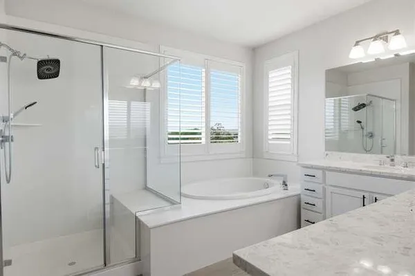 a bathroom with a tub sink shower and mirror