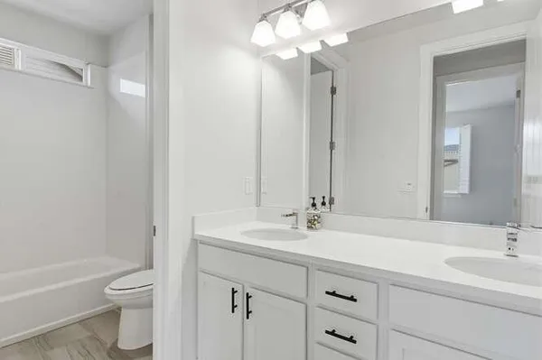 a bathroom with a double vanity sink toilet mirror and bathtub