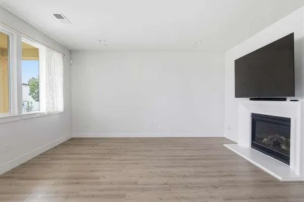 a view of empty room with wooden floor and fireplace