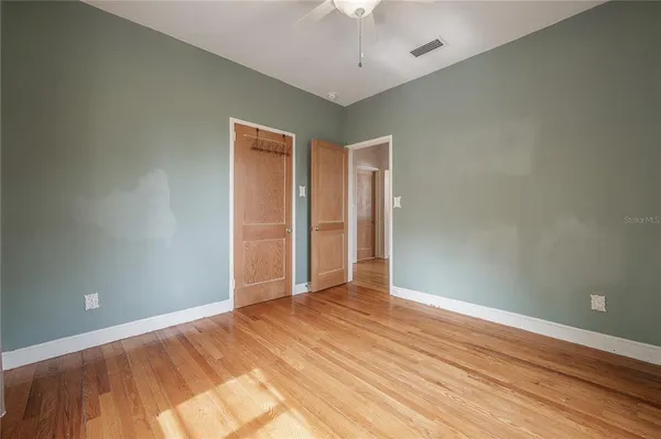 an empty room with wooden floor and fan