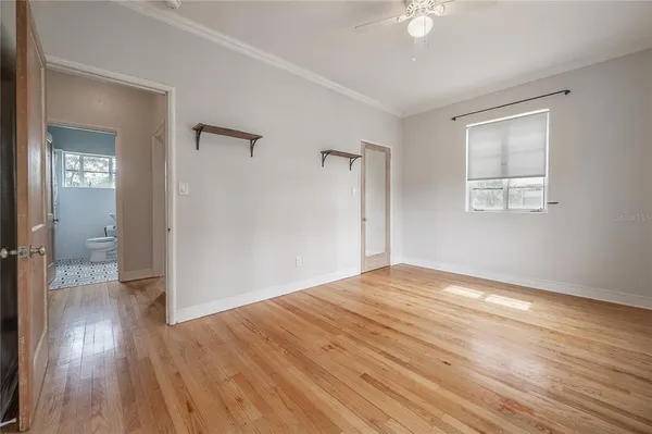 a view of empty room with wooden floor and fan