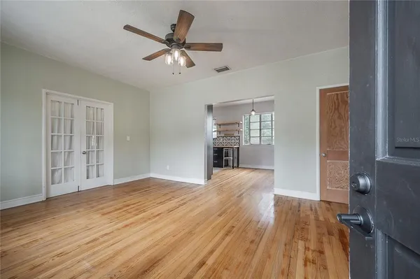 a view of empty room with wooden floor and fan