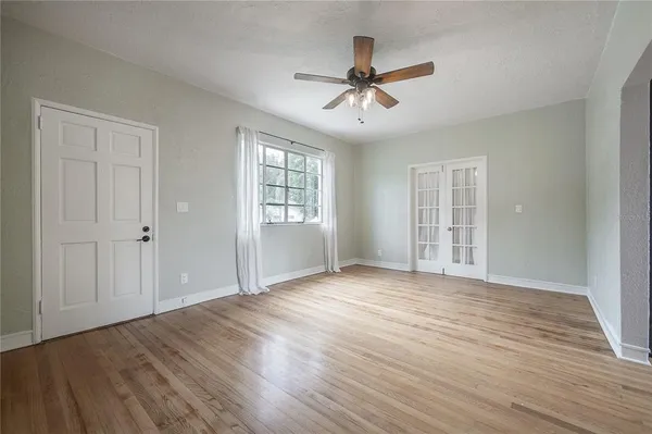 a view of an empty room with wooden floor and a window