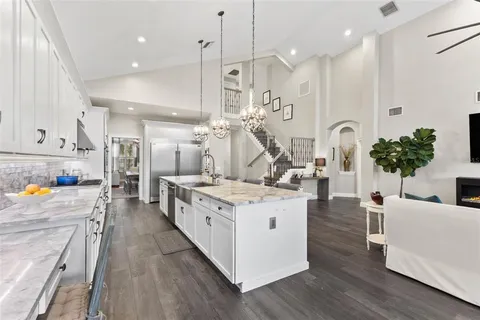 a large kitchen with granite countertop a sink dishwasher a stove and white cabinets with wooden floor