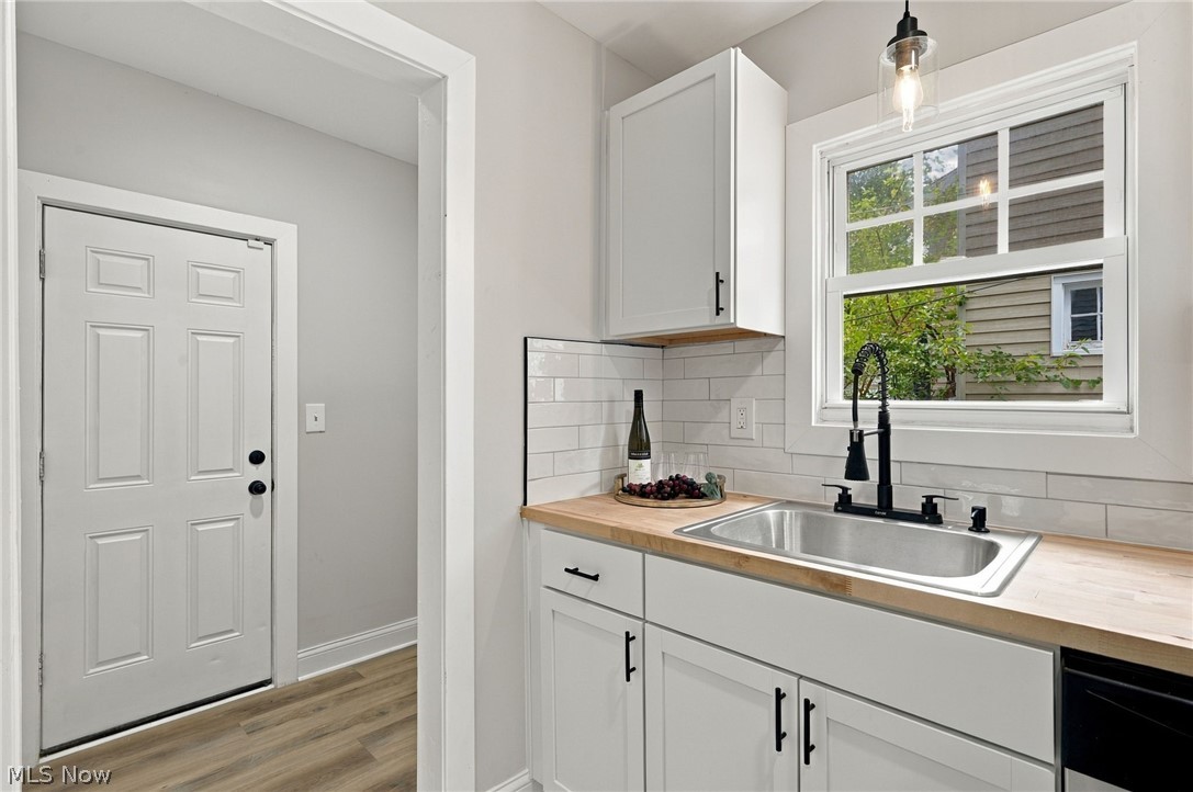 1173 Yellowstone Road Cleveland Heights, OH 44121 - Photo 18 of 44 White shaker cabinetry, wood-finish countertops, subway tile backsplash, stainless steel sink with matte black faucet, and wood-finish flooring