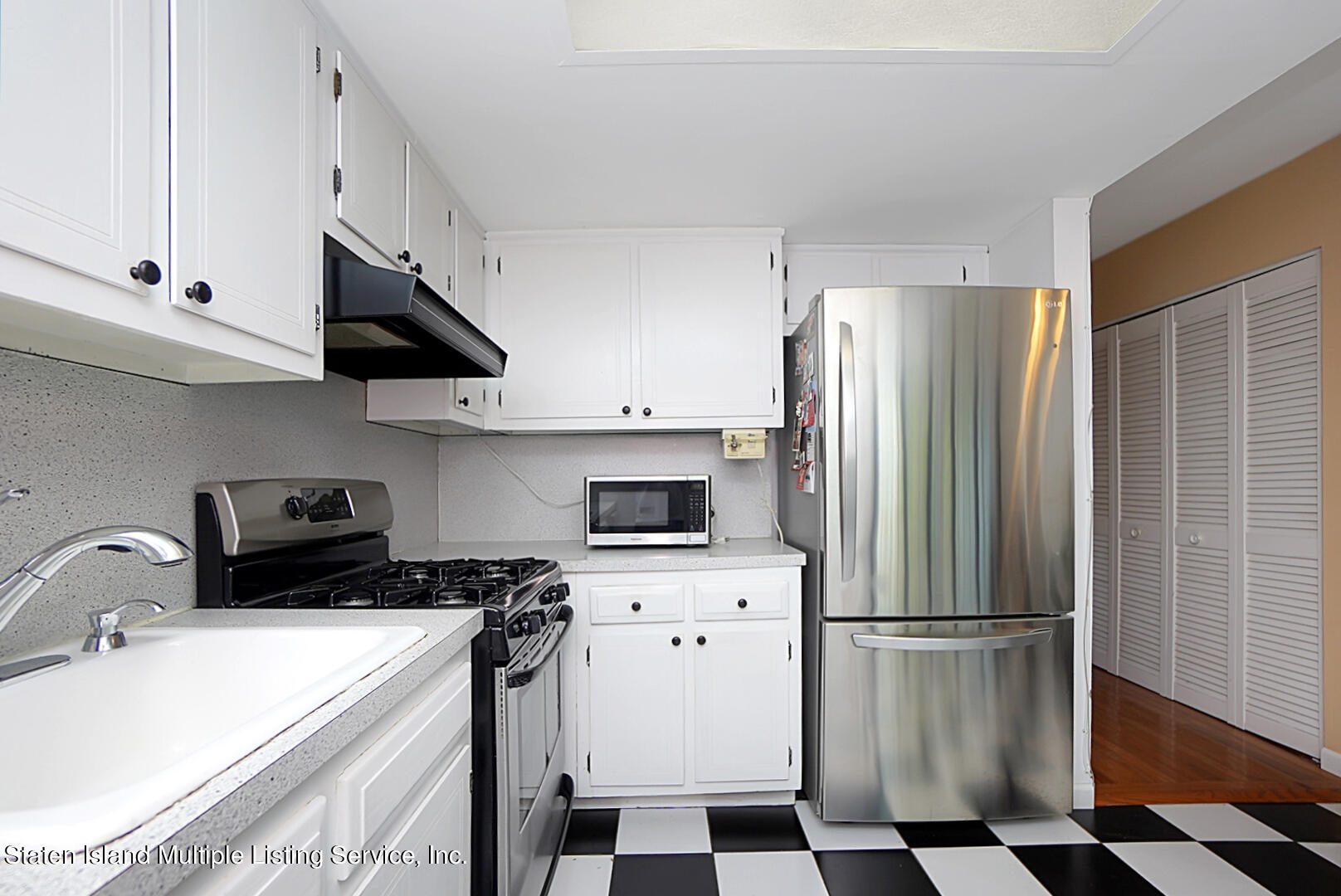 96 Hampton Green Staten Island, NY 10312 - Photo 10 of 24 a kitchen with stainless steel appliances a refrigerator a sink a stove and white cabinets