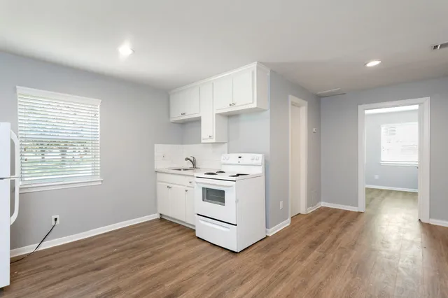 a kitchen with wooden floors and white cabinets