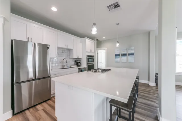 a kitchen with stainless steel appliances a refrigerator a stove a sink a dining table and chairs