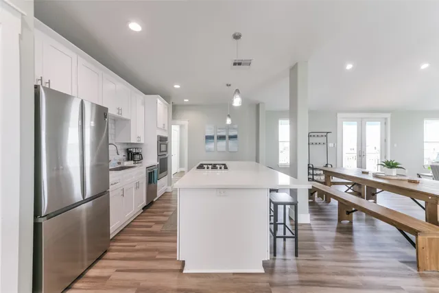 a large white kitchen with wooden floor and a refrigerator