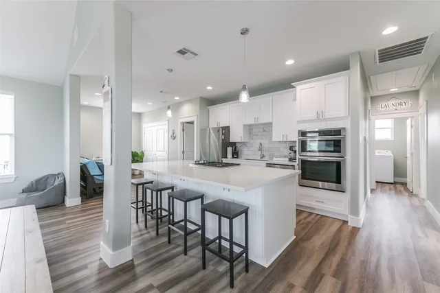 a kitchen with stainless steel appliances granite countertop a stove refrigerator and a dining table with wooden floor