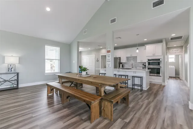 a living room with stainless steel appliances furniture wooden floor and a table