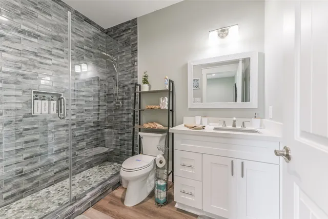 a bathroom with a granite countertop toilet sink mirror and shower
