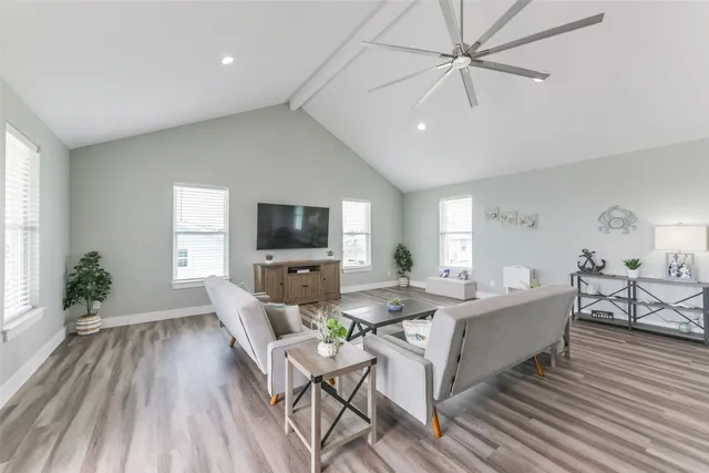 a living room with furniture a flat screen tv and a wooden floor
