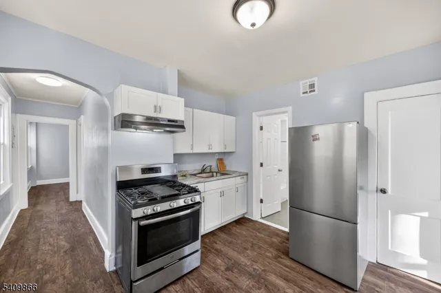 a kitchen with stainless steel appliances a refrigerator a stove and white cabinets