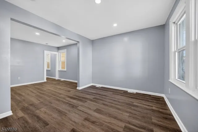 a view of an empty room with window and wooden floor
