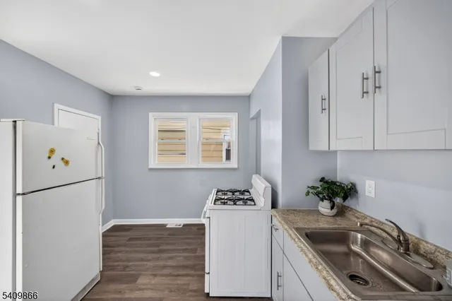 a kitchen with granite countertop a sink a refrigerator a stove a microwave and cabinets