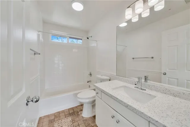 a bathroom with a granite countertop sink a toilet and shower