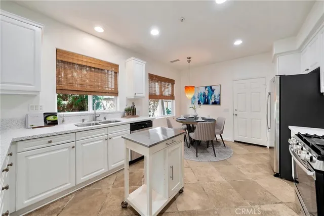 a large white kitchen with furniture a window and stainless steel appliances