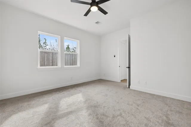 an empty room with windows and fan