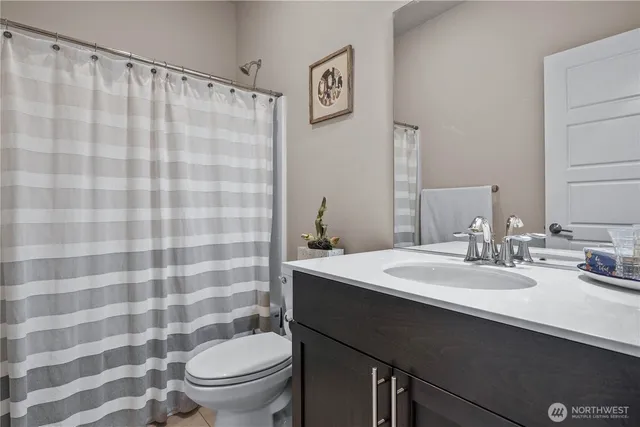 a bathroom with a sink a toilet a mirror and shower curtain