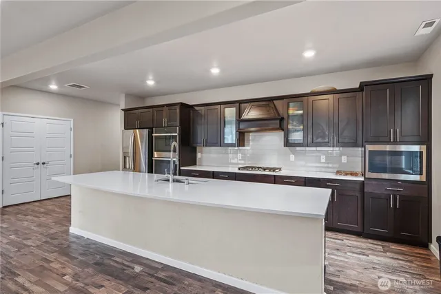 a large kitchen with stainless steel appliances a large counter top a stove and a refrigerator