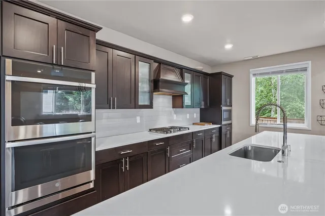 a kitchen with stainless steel appliances granite countertop a sink stove and cabinets