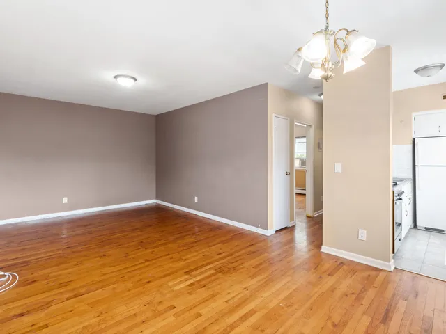 a view of an empty room with wooden floor and a chandelier