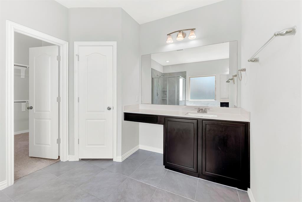 7640 Rhyner Way Fort Worth, TX 76137 - Photo 23 of 40 Spa-inspired primary bathroom featuring a dark wood dual-vanity with white quartz countertop, polished chrome fixtures, and large framed mirror with integrated lighting