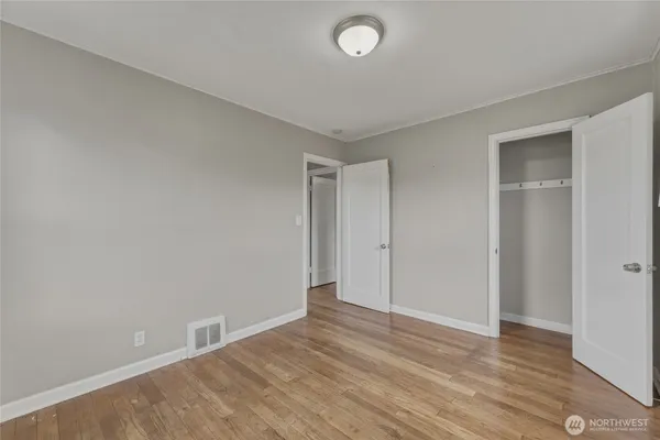 a view of an empty room with wooden floor and closet