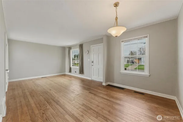 a view of an empty room with wooden floor and a window
