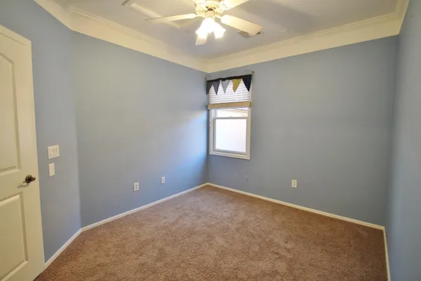 a view of an empty room with window and chandelier fan
