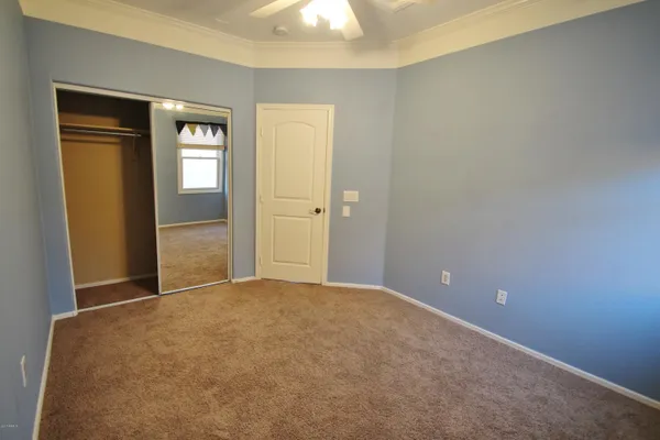 an empty room with closet and a chandelier fan