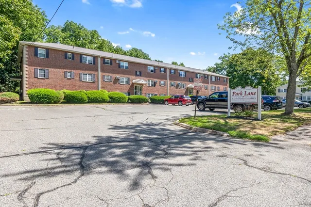 a front view of a building with garden and trees