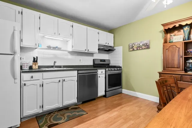 a kitchen with stainless steel appliances granite countertop a refrigerator sink and white cabinets